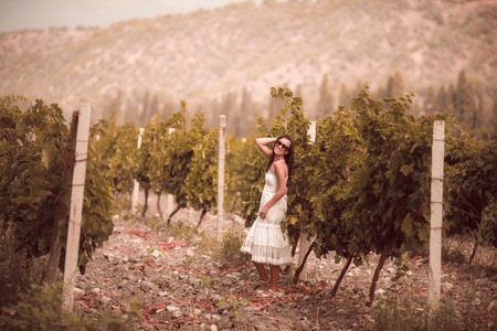 Smiling woman in white dress standing in vineyardの写真素材