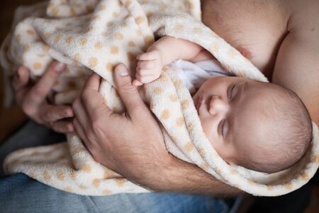 Young father holding his sweet adorable sleeping newborn child