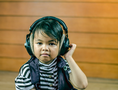 Beautiful asian girl listening music in the wood roomの写真素材
