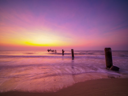 Beautiful sunrise on the beach with old concrete bridge pillars. breakwater in the foregroundの写真素材