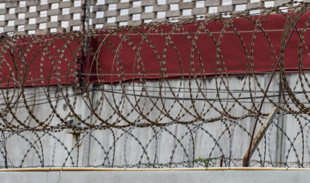 Barbed wire fence on the wall of a building as a backgroundの写真素材