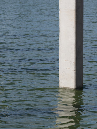 Concrete pillar in the water, blue sky background, close up