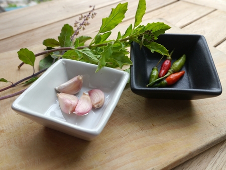 Paprika, garlic, basil, sliced vegetables on a cutting board.の写真素材