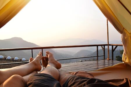 Foot view, A couple sleeping in a tent and looking at the mountain view in the morning. Holiday Relax concept.の写真素材