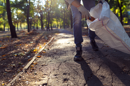 young man picking up trash outdoor. close upの写真素材