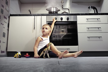 accident prevention. The child unattended playing in the kitchen with a gas stove.の写真素材