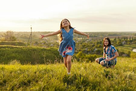 Little girl running on meadow with sunsetの写真素材