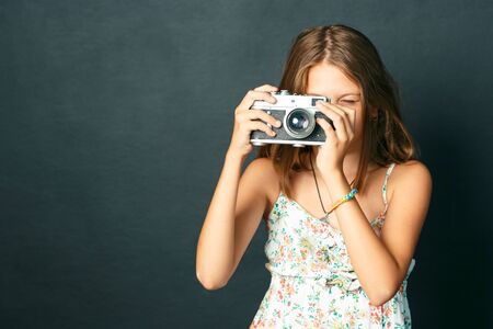 beautiful smiling child (girl) with white teeth holding a instant cameraの写真素材