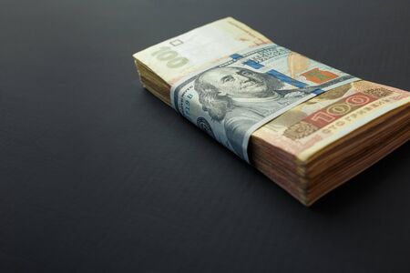 Value of Ukrainian hryvnia and American dollars. A pack of Ukrainian hryvnia wrapped one hundred dollar billの写真素材