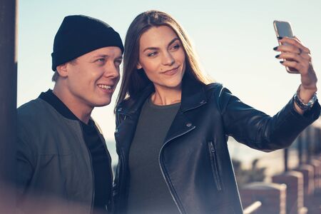 A young loving couple spends fun time by the sea and makes selfies. Man and woman have spring...