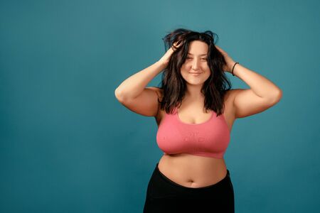 Happy plus size positive woman. Happy body positive concept. I love my body. Attractive overweight woman posing on camera in the studio on a colored background. Girl is wearing a coral braの写真素材