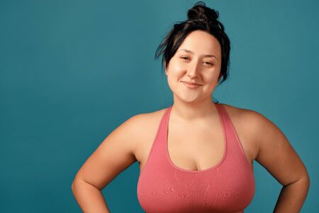 Happy plus size positive woman. Happy body positive concept. I love my body. Attractive overweight woman posing on camera in the studio on a colored background. Girl is wearing a coral braの写真素材