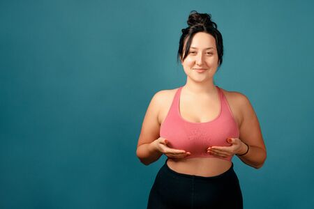 Happy plus size positive woman. Happy body positive concept. I love my body. Attractive overweight woman posing on camera in the studio on a colored background. Girl demonstrates her natural bubsの写真素材