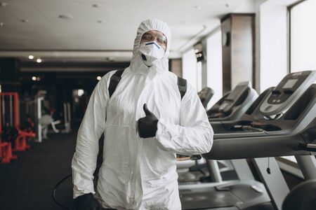 Cleaning and Disinfection in crowded places amid the coronavirus epidemic Gym cleaning and disinfection Infection prevention and control of epidemic. Protective suit and mask and spray bagの写真素材