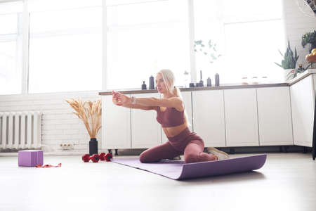 young beautiful blonde takes care of her body while at home during quarantine. She trains people...
