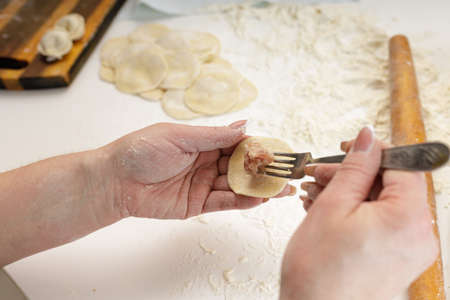 homemade dumplings in the kitchen without decorations. making dumplings with minced pork, beef and chickenの写真素材