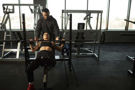 A disabled girl is engaged in the gym A woman with one leg trains with a trainer, she works hard and...
