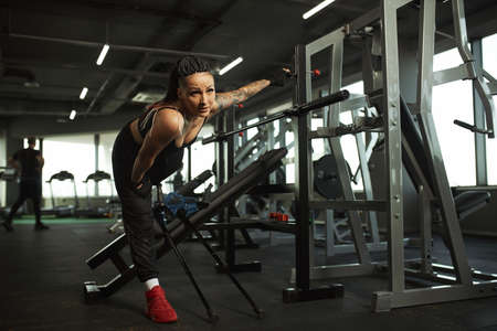 A disabled girl is engaged in the gym A woman with one leg trains with a trainer, she works hard and...