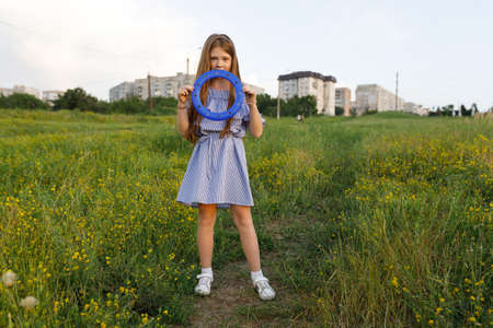 young red-haired mom and her red-haired daughter launch a throwing saucer outdoors during sunsetの写真素材