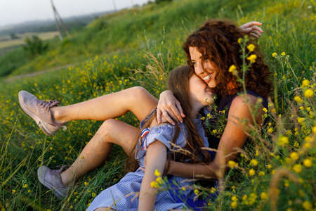 young red-haired mom and her wonderful red-haired daughter have fun outdoors dressed in dressesの写真素材