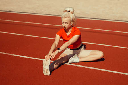 young beautiful girl doing warm-up before sports exercise at school stadium