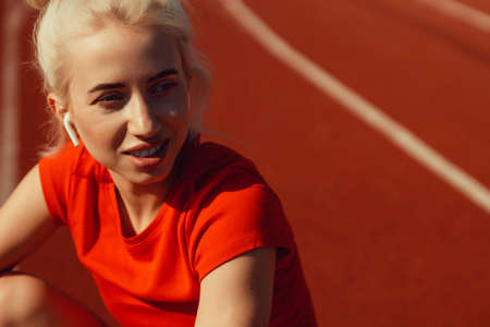 close-up portrait of a beautiful blonde who is sitting on a jogging trackの写真素材