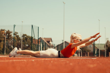 young blonde shakes abdominal muscles on a sports mat on the streetの写真素材