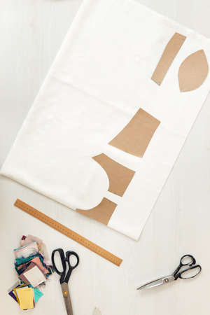 Close up. hands woman Tailor working cutting a roll of fabric on which she has marked out the pattern of the garment she is making with tailors chalk.の写真素材