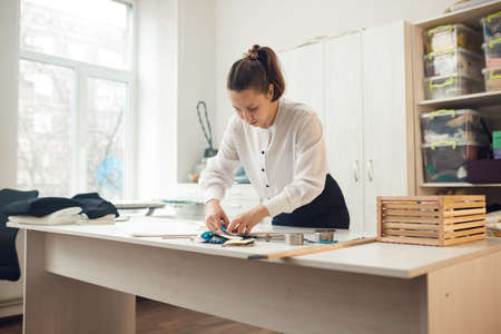 a young girl seamstress applies a sketch with a piece of soap on the fabric from which she will sew clothesの写真素材