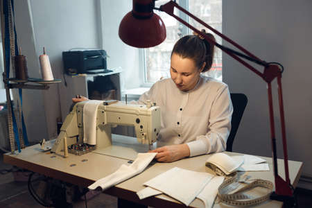 young girl seamstress while working on tailoring in her workshopの写真素材