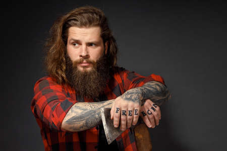 handsome man with long hair with an ax in his hands on a dark studio background.