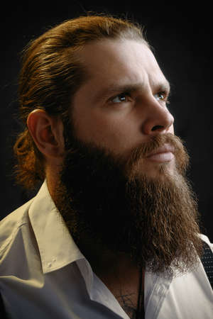 close-up portrait of a brutal man with a beard and long hair he looks up.