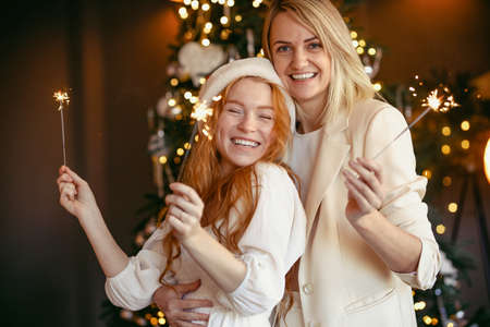 lesbian couple having dinner celebrating a holiday Girls burn sparklers and smile at the camera