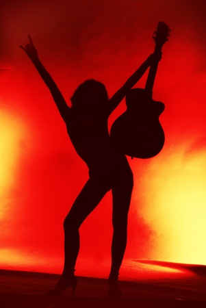 Woman with guitar silhouette on red background の写真素材