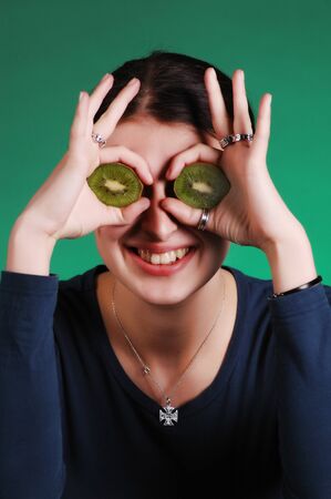 Young woman holds kiwi in front of her eyes の写真素材