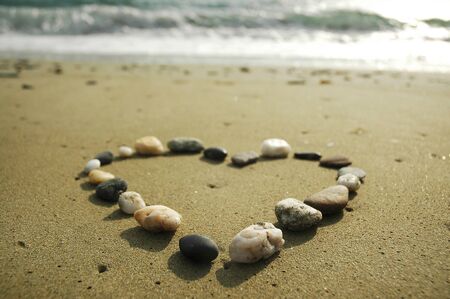 Heart made of stones on a sand backgroundの写真素材