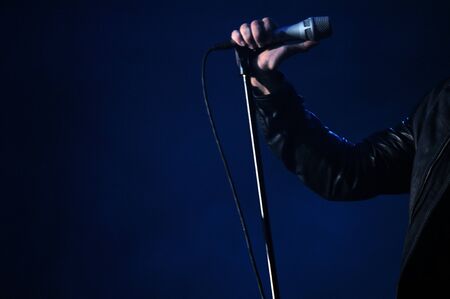 Hand holding microphone for singing with dark backgroundの写真素材