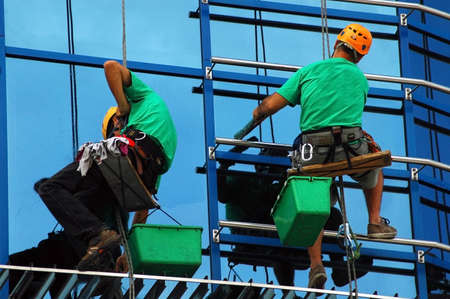 CLUJ NAPOCA – MAY 03: Unidentified workers washing the windows facade of a new build bank before...