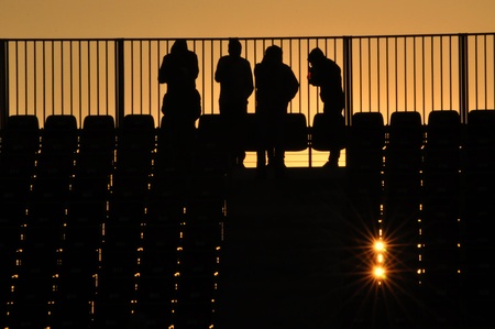 People silhouette at a stadium in the sunset
