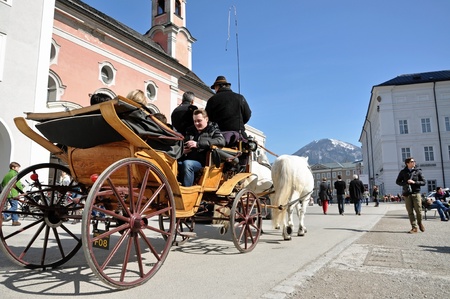 SALZBURG - MARCH 13: Horse driven carriage with tourists in Mozart square, visiting the famous city of Salzburg, part of Unesco heritage where the composer, W.A. Mozart was born. On March 13, 2012 in Salzburg, Austriaのeditorial素材