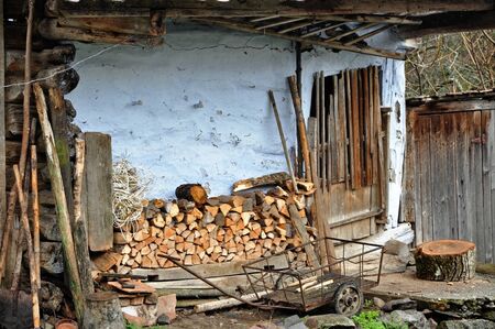 Pile of firewood stocked near an old barn