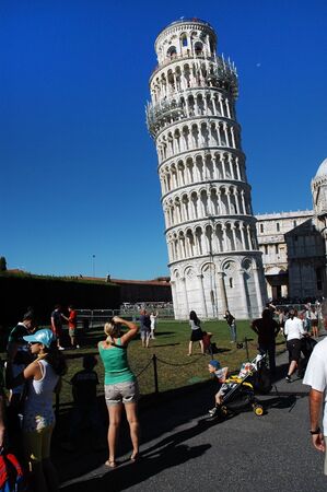 PISA, ITALY â AUGUST 31: Tourists posing in front of the Leaning tower of Pisa on August 31, 2010 in Pisa, Italy. The Leaning Tower is one of the major tourist attractions of Italyのeditorial素材