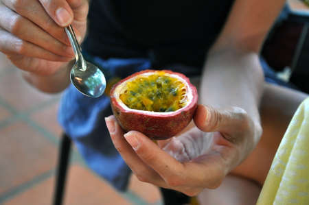 Girl eating a passion fruit with a spoon