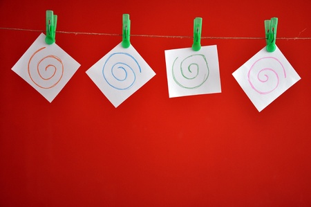 Collection of note papers clipped on the rope in front of red background の写真素材