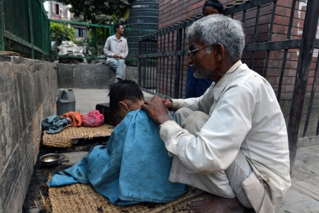 KATHMANDU, NEPAL  SEPTEMBER 28  Unidentified street barber cutting the hair of a child in the streets of Kathmandu on Sept 28, 2013 in Kathmandu, Nepal  This custom is very popular the Nepalese society  のeditorial素材