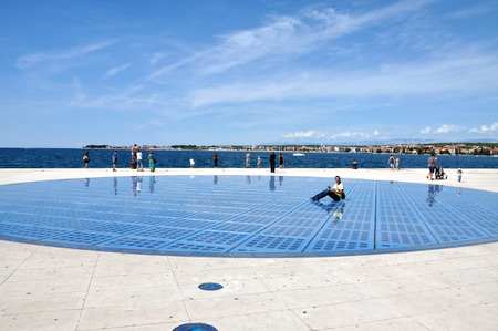 ZADAR - AUGUST 25: People walking on Greeting to the Sun sculpture. It  consists of 300 multilayer glass panels and uses solar power to create a light show that displays at night. On August 25, 2014 in Zadar, Croatiaのeditorial素材