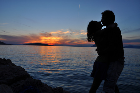 Silhouette couple kissing over sea sunset backgroundの写真素材