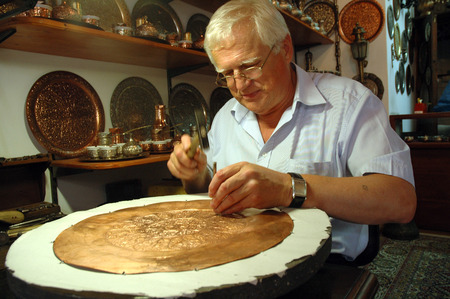 MOSTAR, BOSNIA AND HERZEGOVINA - AUGUST 7: Unidentified craftsman tinkering a copper dish in his small shop in the bazaar. On August 7, 2009 in Mostar, Bosnia and Herzegovinaのeditorial素材