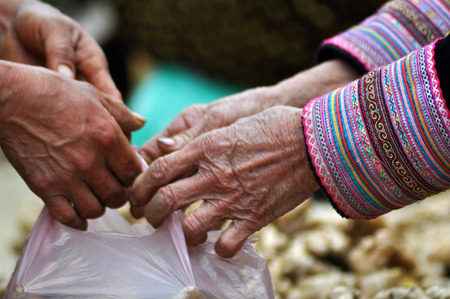 SAPA, VIETNAM - FEBRUARY 22, 2013: Hmong woman selling ginger at Bac Ha market. Bac Ha is hilltribe market where people come to trade for goods in traditional costumesのeditorial素材