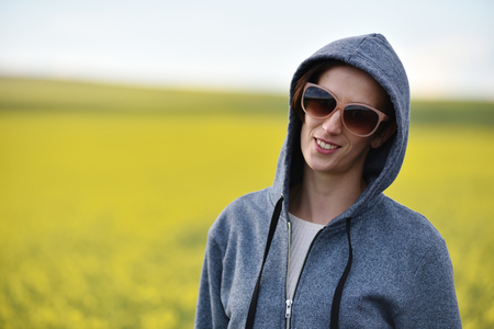 Smiling girl in hoodie and sunglasses in the outdoorsの写真素材